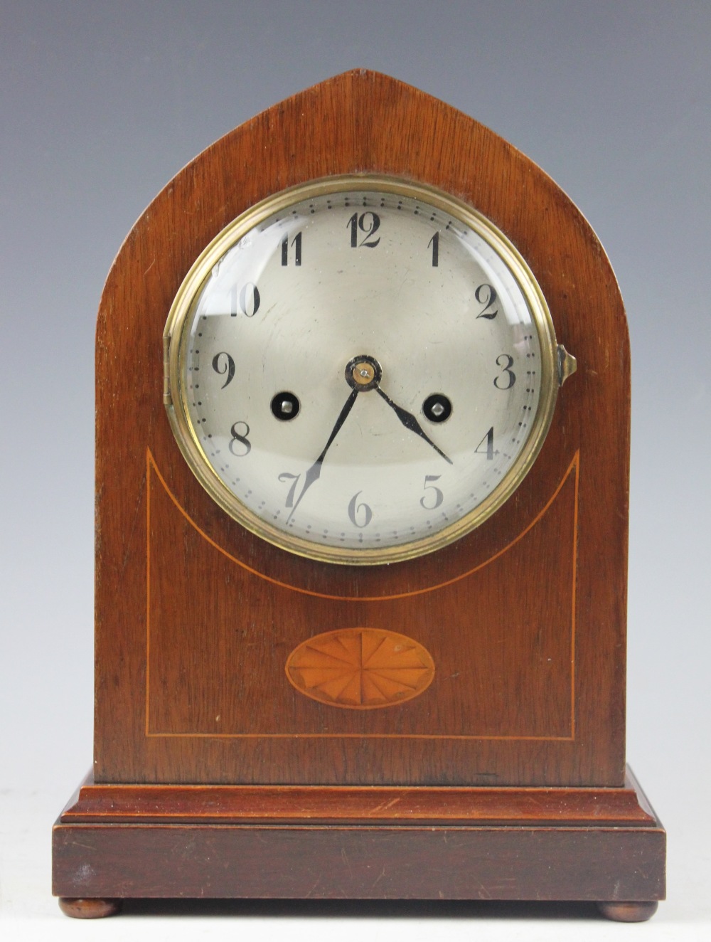 An Edwardian inlaid mahogany lancet shaped mantel clock, with silvered Arabic dial,