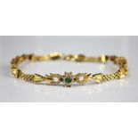 An emerald and white stone set yellow metal bracelet, designed as three floral clusters,