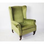 An Edwardian wing back salon chair, with green upholstery, on tapered legs,