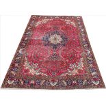 A Persian hand woven wool carpet, worked with an all over floral design against a red ground,