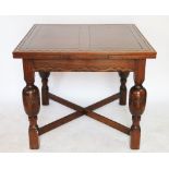 An early 20th century oak drawer leaf dining table, with turned baluster legs and X frame stretcher,