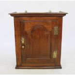 A George III and later oak spice cupboard, with panelled door enclosing a shelf,