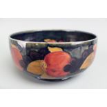 A Moorcroft Pomegranate and Berries bowl, decorated with blooms against an ink blue ground,