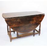 An early 18th century oak gate leg table, with oval top, on turned and block legs,