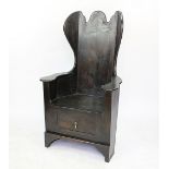 An 18th century style stained pine lambing chair with wing back and solid seat above a drawer,