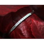 A 9ct white gold bangle, set with nine colourless square cut stones,