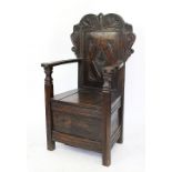 An 18th century style carved oak hall chair / Wainscott chair, with hinged seat on moulded legs,