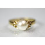An 18ct gold untested pearl and diamond ring, designed as a central pearl, within stepped,