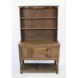 A 1920's carved oak dresser, with two shelves on base with cupboard door and pot shelf,