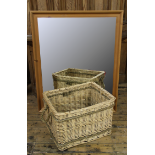 A modern pine wall mirror, with bevelled plate, 113cm H x 92cm W, with a wicker log basket,