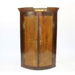 A George III inlaid oak bow front hanging corner cabinet,
