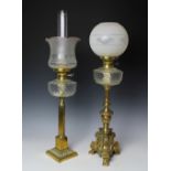 Two brass oil lamps, each with glass reservoir and associated shades,