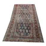 A Persian wool carpet, worked with a central panel of stylised leaves,