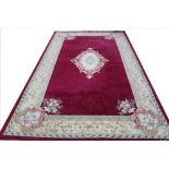 A machine woven wool carpet, worked with a floral medallion against a claret ground,