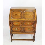 A 1920's oak bureau, with fall over two long fielded drawers, on barley twist legs,