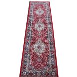 A Kashmir runner, worked with a design of three floral medallions against a red ground,