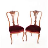 A set of four late Victorian carved walnut dining chairs, with upholstered seats, on cabriole legs,