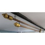 Two fluted mahogany curtain poles, with gilt wood rings and flower head terminals,