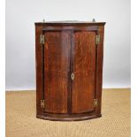 A George III oak bow front corner cabinet,