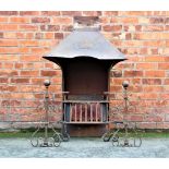 An Arts and Crafts wrought iron fire place, the swept hood decorated with stylised leaves,