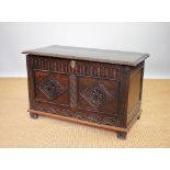 An 18th century style carved oak coffer, 1920's, with panelled front, on stile feet,