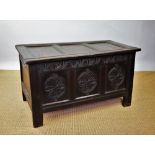 An early 18th century oak coffer, with triple panelled top and carved panelled front, on stile feet,