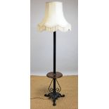 A walnut and iron standard lamp, with circular shelf, on triform scroll base,