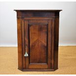 A Gorge III oak hanging corner cabinet, with moulded cornice and panelled door,