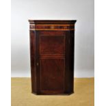 A George III inlaid mahogany corner cabinet, the cornice with inlaid panel of flowers,