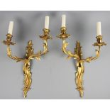A pair of Louis XV style gilt brass twin branch wall lights, with serpentine back plates,