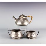 An Arts and Crafts pewter three piece tea service designed by Archibald Knox,