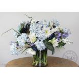 A silk flower arrangement of large proportions, including hydrangeas, roses and lilies,