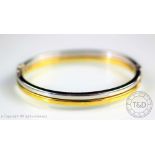 A 9ct bi-colour gold bangle, designed in half white and half yellow gold, clasp with safety catch,