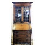 A 1920's oak bureau bookcase with two lead glazed doors above a fall and three long drawers,