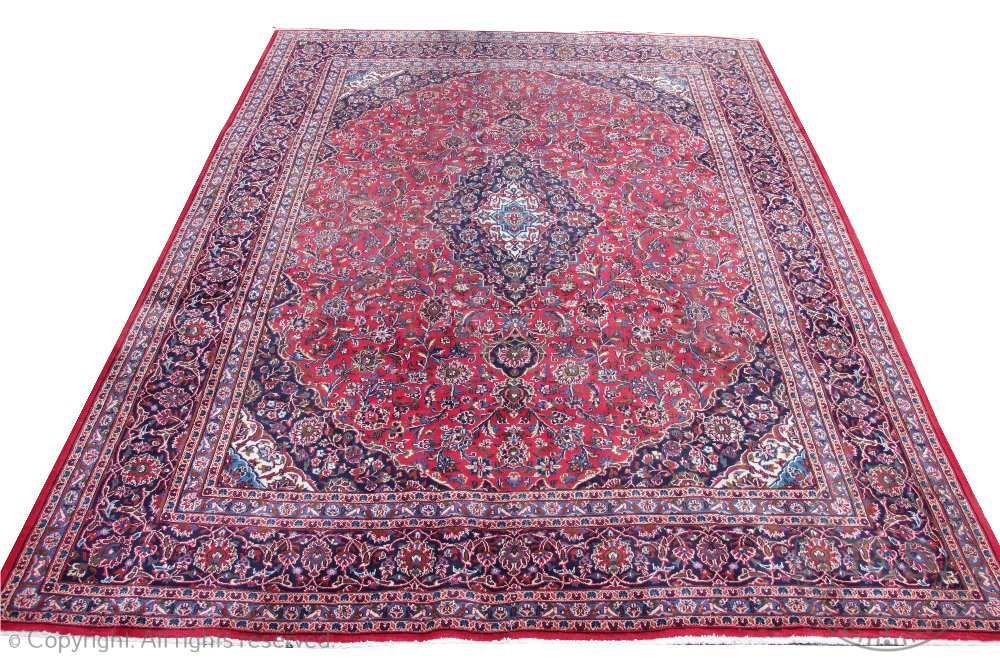 A large Persian Kashan wool carpet, worked with an all over floral design against a red ground,