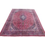 A large Persian Kashan wool carpet, worked with an all over floral design against a red ground,