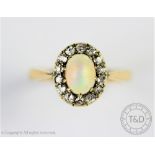 An opal and diamond oval cluster ring, the central oval opal within a diamond set surround,