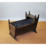 An 18th century oak cradle, with turned finials and panelled top and sides,