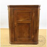 A George III oak hanging corner cabinet, with panelled door,