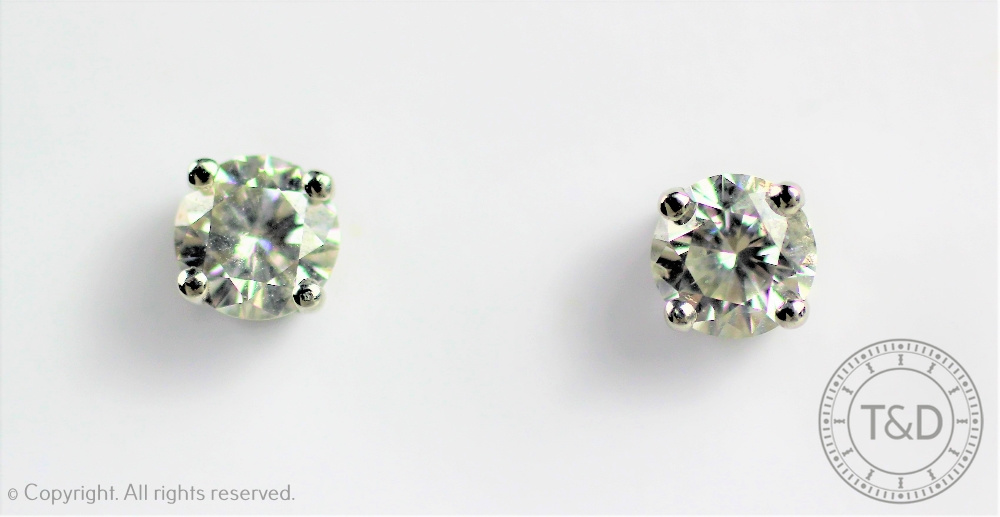 A pair of diamond solitaire earrings,
