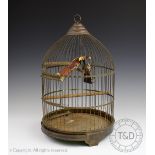 A brass bird cage, possibly French, the swing set with two carved and painted birds,