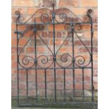 A black painted wrought iron garden gate, with scroll detail,