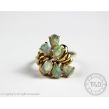 An opal six stone cluster ring, the six pear shaped opals within decorative ribbon mount,