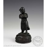 A Chinese bronze figure, late 17th century, modelled as a boy stood in prayer position,