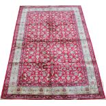 A Kashmir rug, worked with an all overall floral design against a red ground,