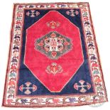 A Persian wood tribal rug, worked with a red medallion against a blue ground,