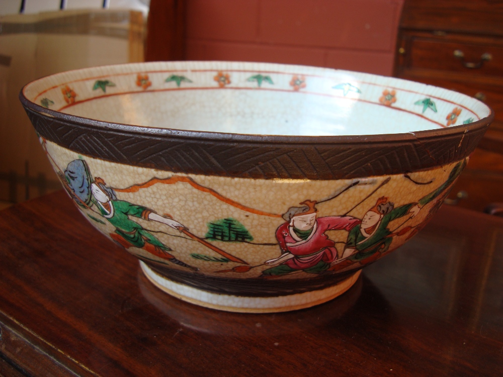 A crackle glazed oriental bowl depicting a battle, with heavy restoration to one side.