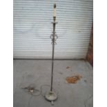 An ornate metal standard lamp on three splayed feet, the base having rose decorations. A/F.