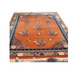 A fringed Chinese rug, orange ground with various colours. 276 x 203cm.