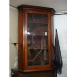 A mahogany glass fronted corner cabinet.